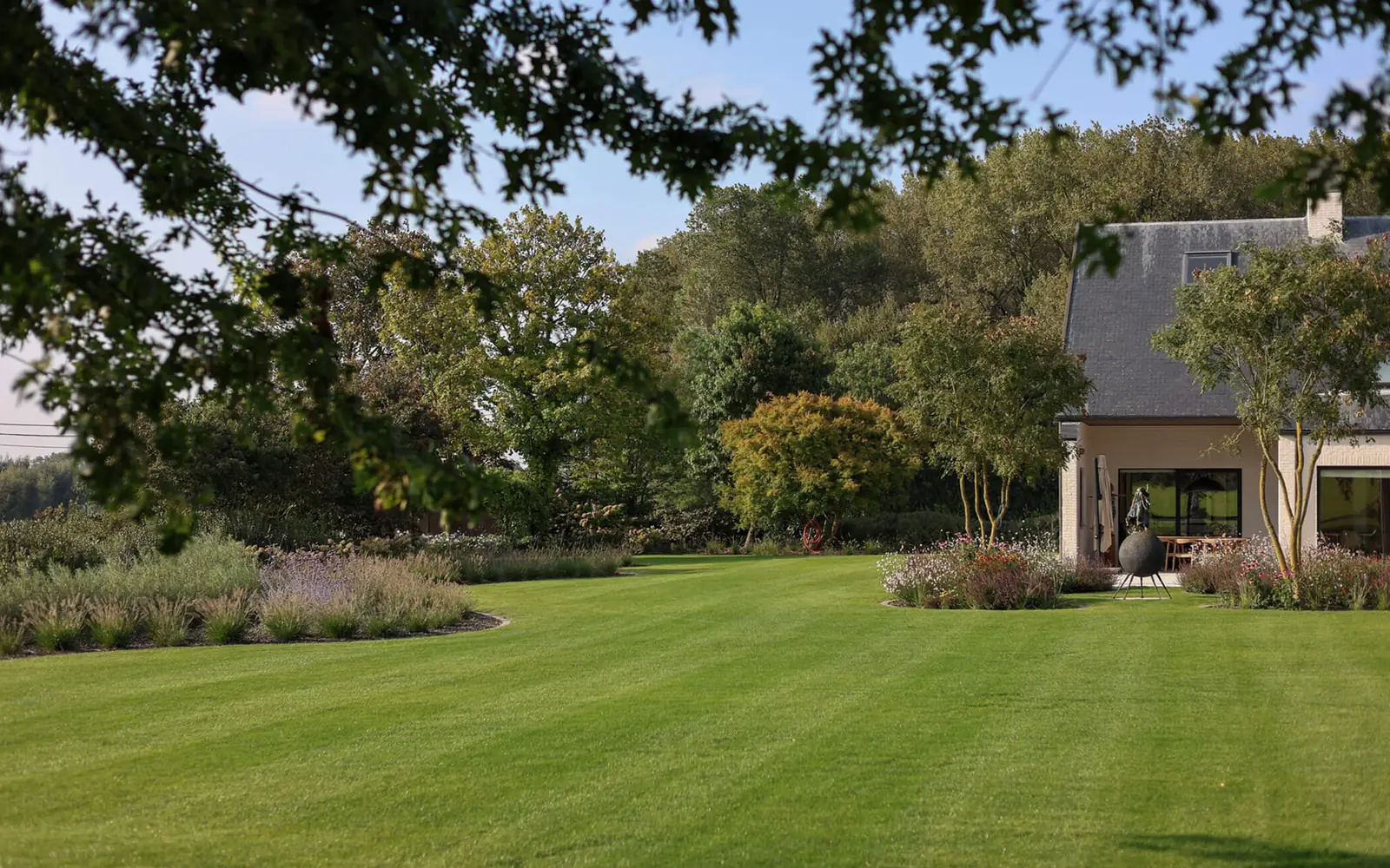 Landschapstuin van Arte-Verde met gestreept gazon en villa in warm namiddaglicht
