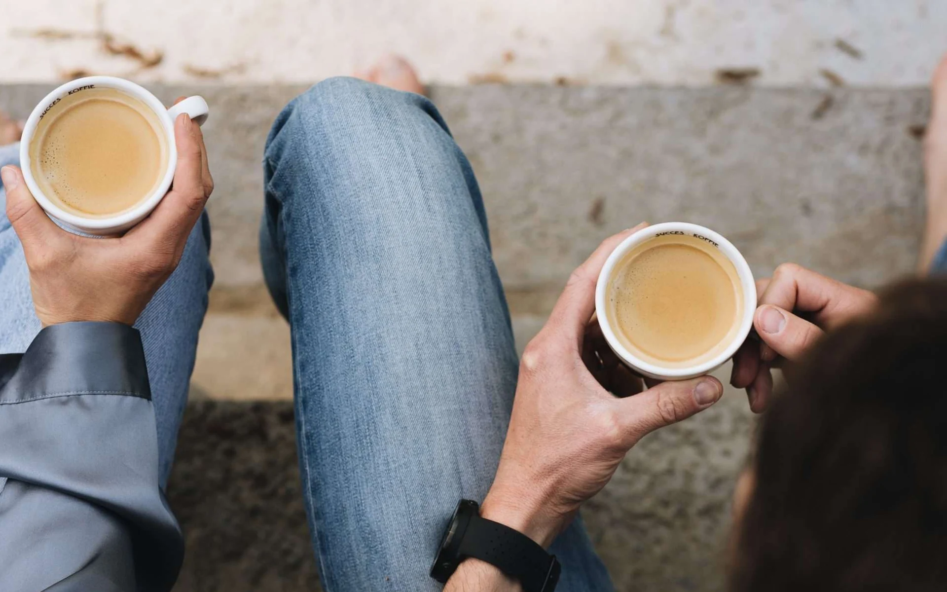 Twee mensen drinken espresso uit Succes Koffie-kopjes op een stenen trap